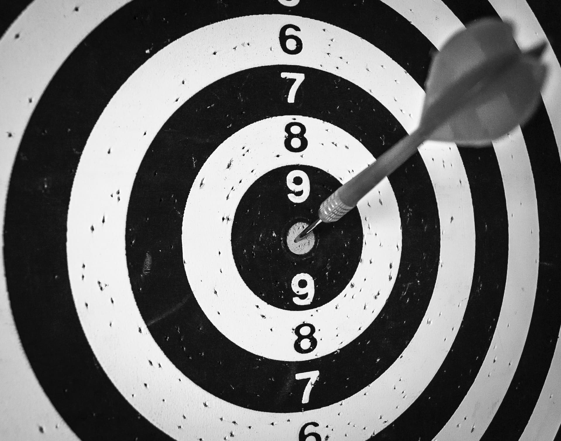 black and white dartboard with a single dart in the bullseye