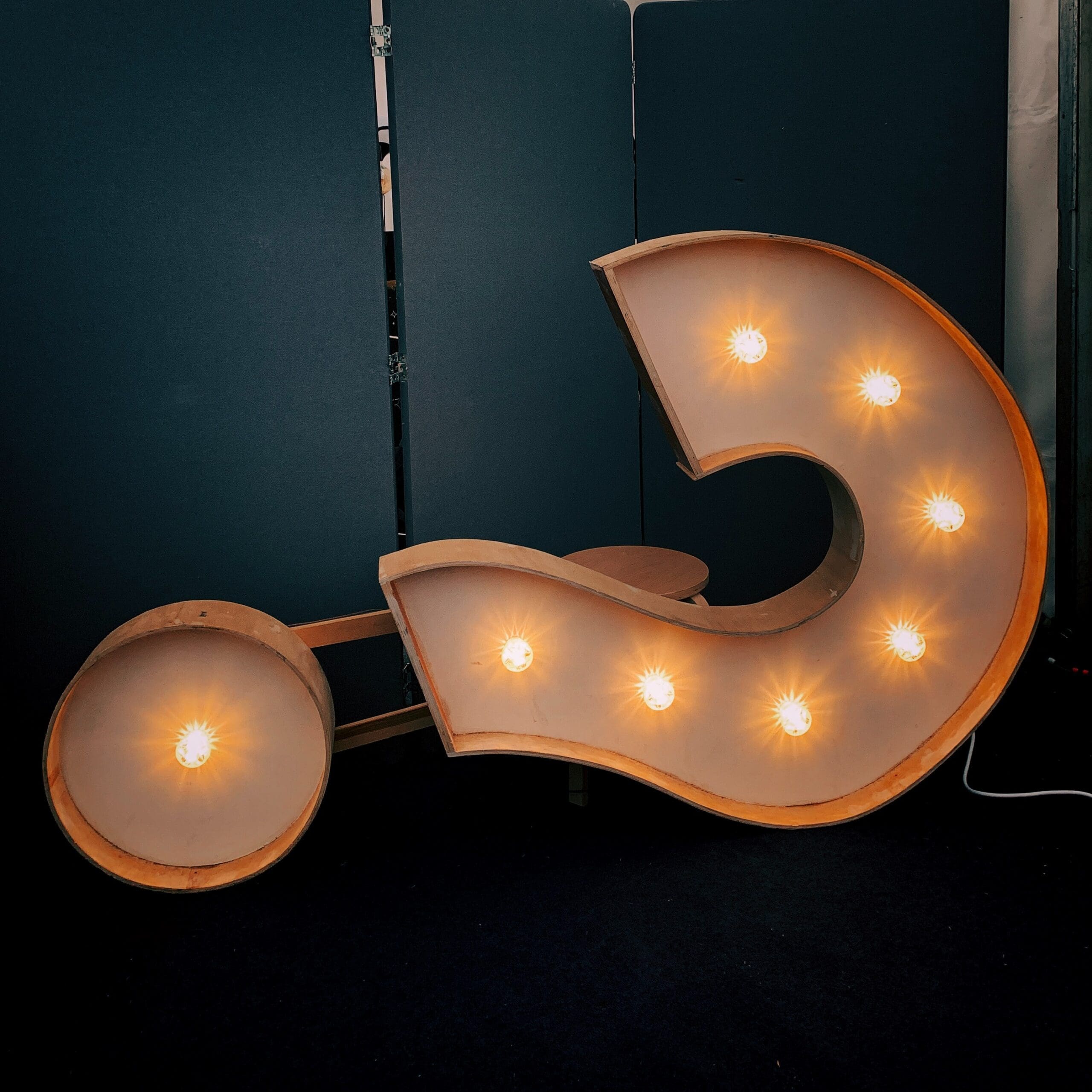 a retro lighting sign in the shape of a question mark
